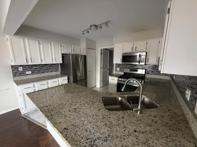 a kitchen with kitchen island granite countertop a stove a sink and a refrigerator