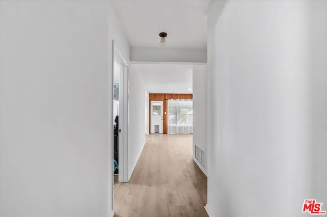a view of a hallway with wooden floor and a white door