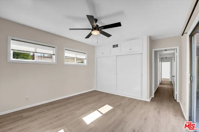 a view of empty room with wooden floor and ceiling fan