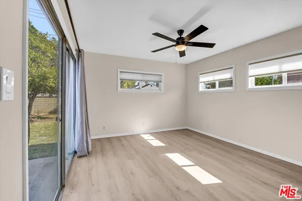 an empty room with wooden floor fan and windows