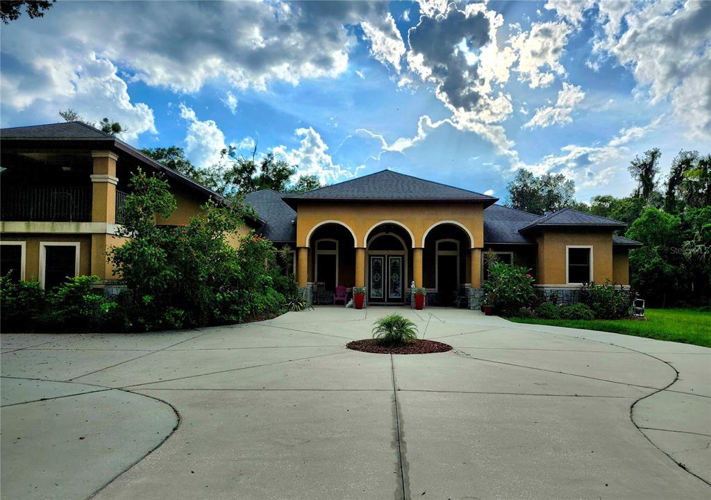 a front view of a house with yard and trees around