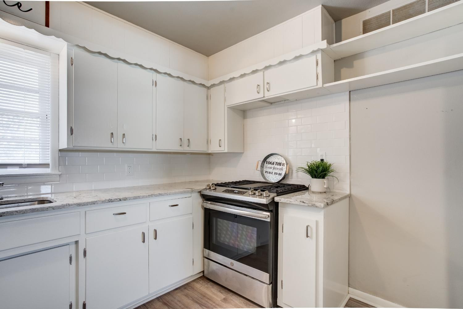4629 Elgin Avenue Lubbock, TX 79413 - Photo 13 of 34 a kitchen with granite countertop white cabinets stainless steel appliances and a window
