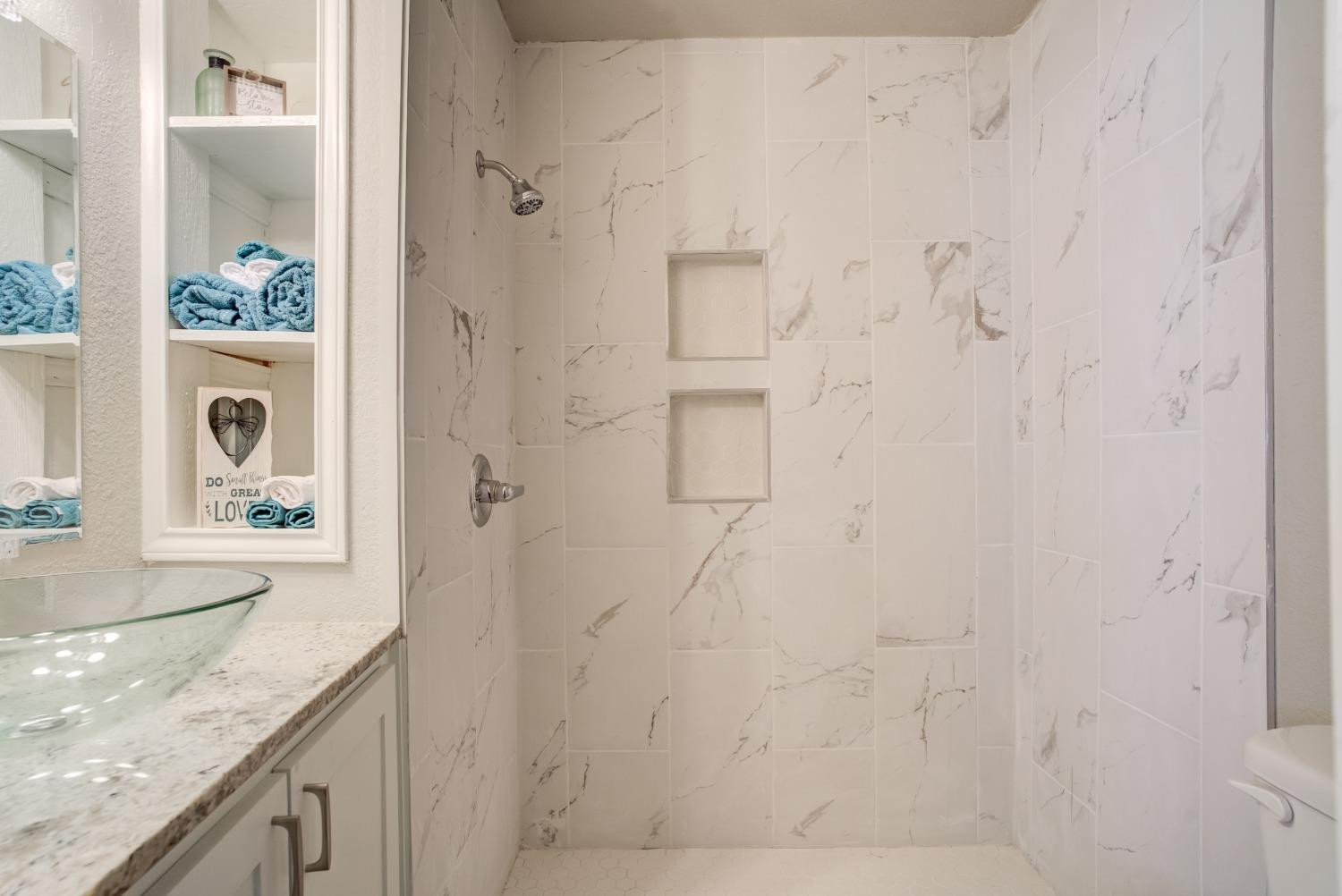 4629 Elgin Avenue Lubbock, TX 79413 - Photo 26 of 34 a bathroom with a granite countertop sink a vanity and shower