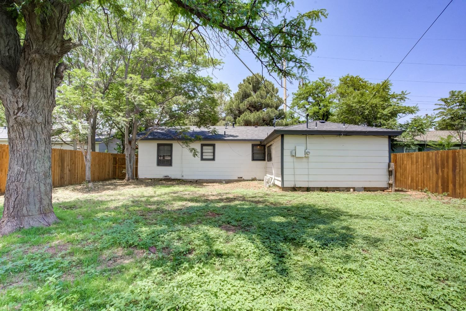 4629 Elgin Avenue Lubbock, TX 79413 - Photo 34 of 34 a backyard of a house with large trees and wooden fence