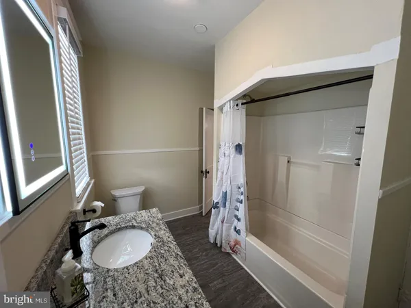 a bathroom with a granite countertop sink toilet and shower