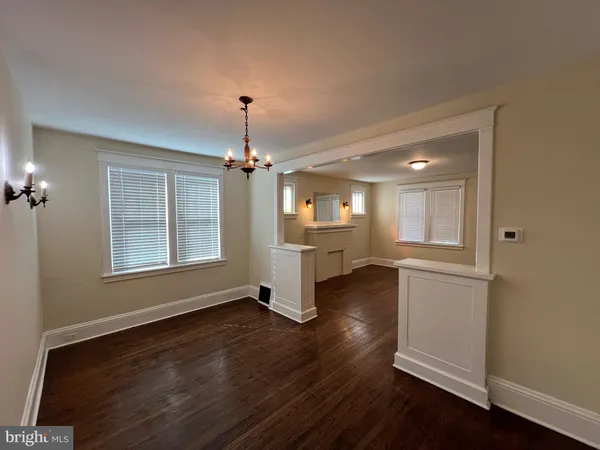 an empty room with wooden floor chandelier and windows