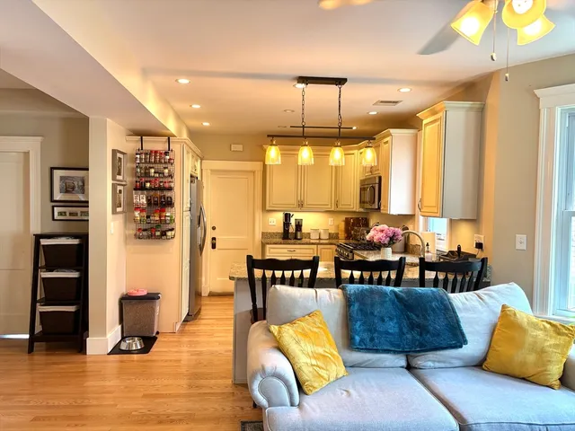 a living room with furniture kitchen view and large wooden floor