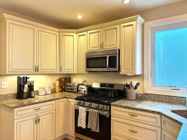 a kitchen with stainless steel appliances granite countertop white cabinets sink and a granite counter top