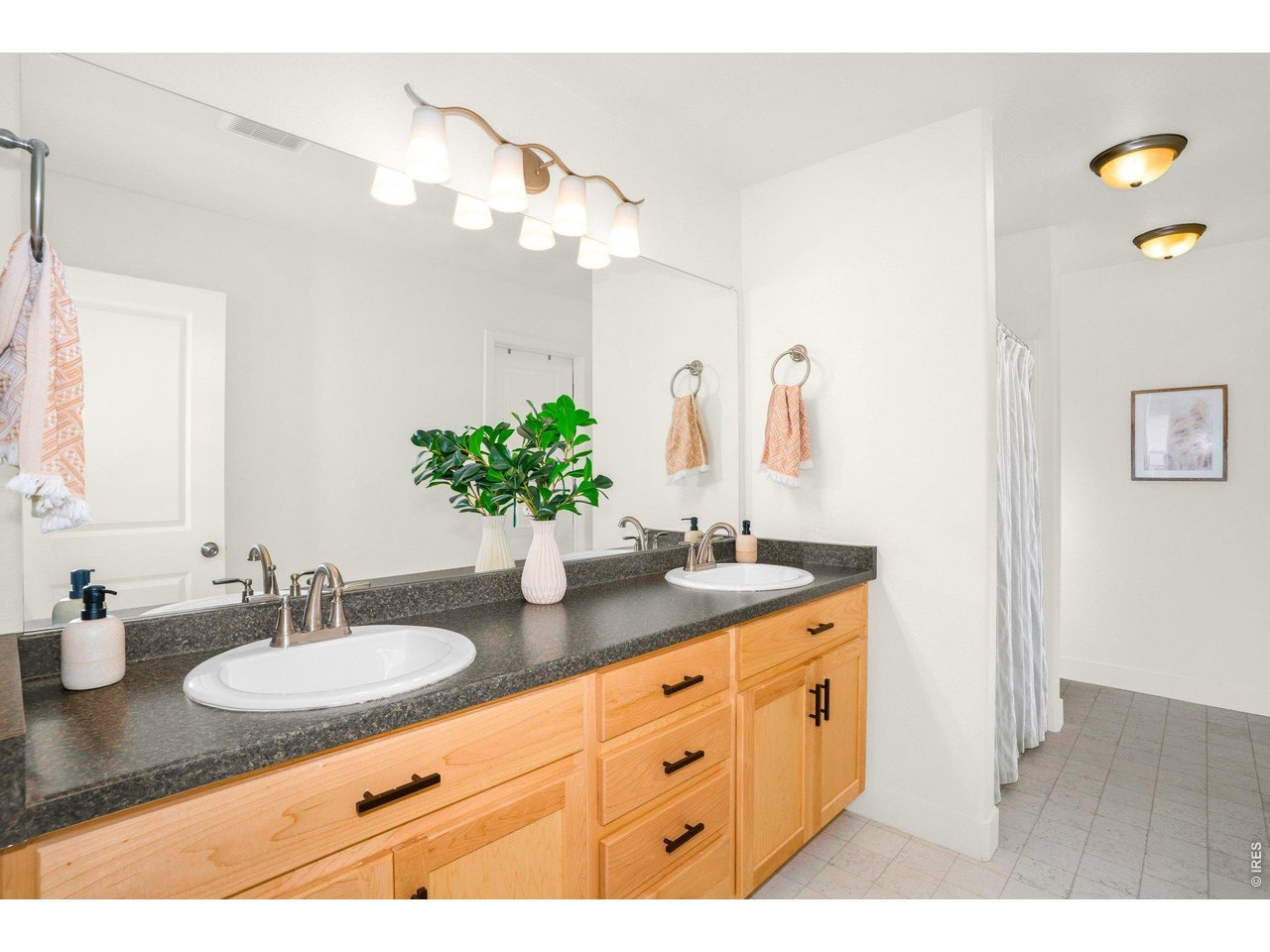 934 Milner Pass Road Severance, CO 80550 - Photo 14 of 33 The on-suite bath showcases a blend of warmth and modern style, featuring rich brown wood cabinetry accented by sleek black pulls for a striking contrast. A spacious dual sink vanity offers both function and elegance.