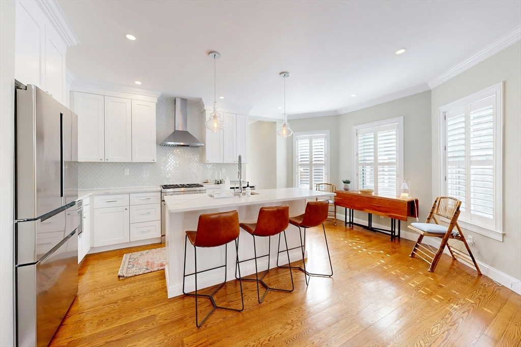 96 Floral Street, Unit 1 Newton, MA 02461 - Photo 11 of 42 a large white kitchen with stainless steel appliances granite countertop a stove a sink a dining table and chairs