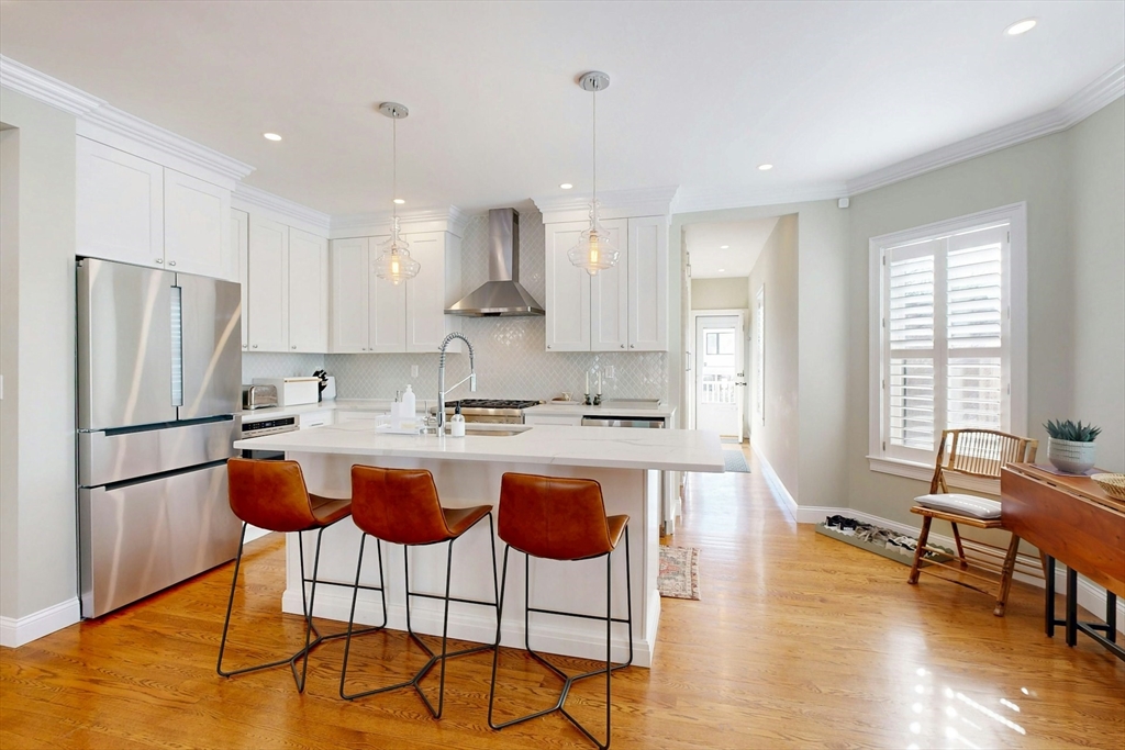 96 Floral Street, Unit 1 Newton, MA 02461 - Photo 12 of 42 a kitchen with stainless steel appliances granite countertop a refrigerator a stove a sink a dining table and chairs with wooden floor
