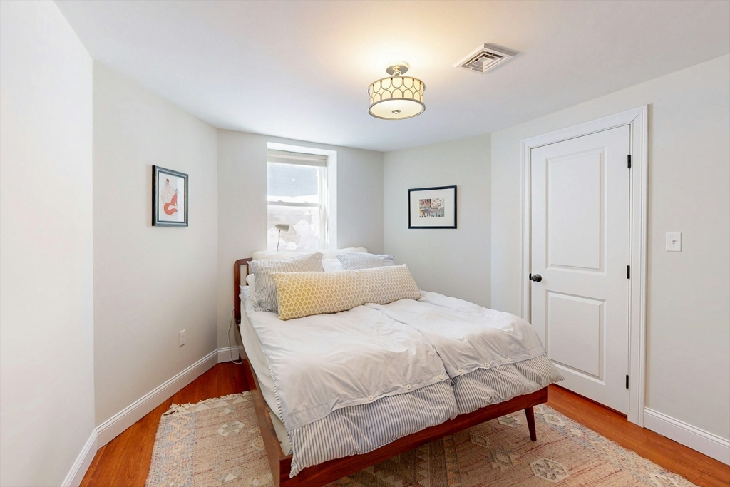96 Floral Street, Unit 1 Newton, MA 02461 - Photo 33 of 42 a bedroom with a bed and a lamp on dresser
