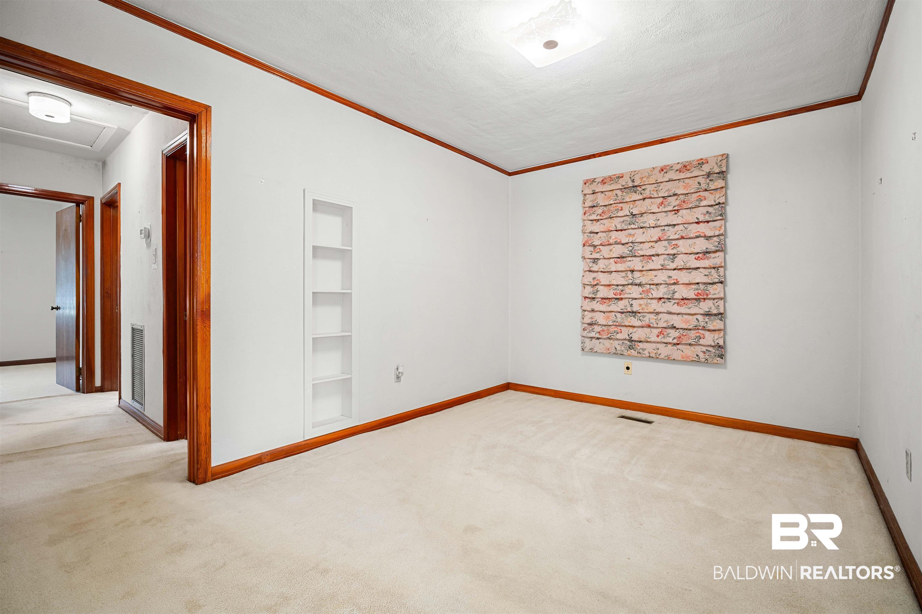 2300 Ellen Drive Mobile, AL 36605 - Photo 13 of 25 Unfurnished room with built in shelves, crown molding, light carpet, and a textured ceiling