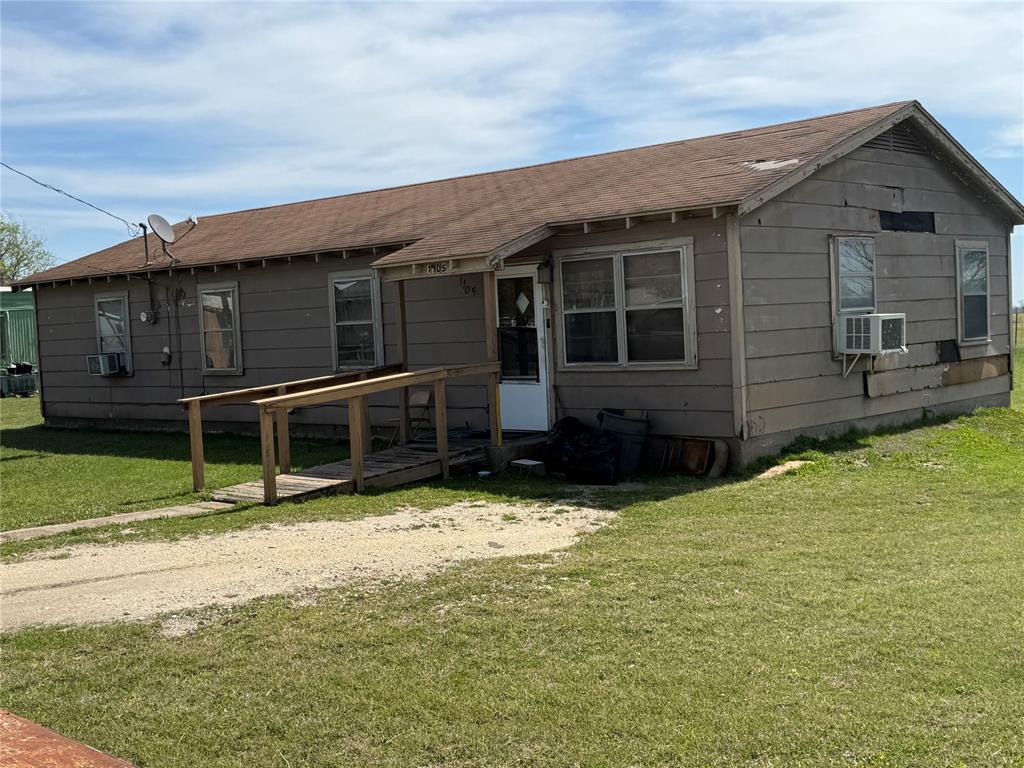 1105 Shabazz Street Milford, TX 76670 - Photo 5 of 6 View of front of property featuring a front lawn, roof with shingles, a wooden deck, and cooling unit