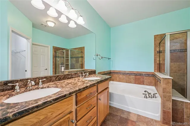 a bathroom with a granite countertop bathtub a sink and a large mirror