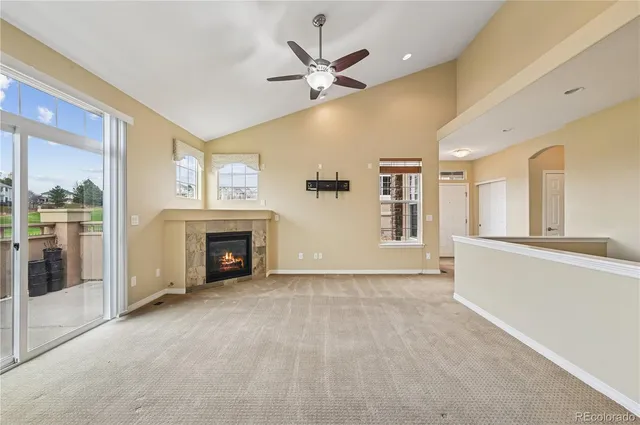 a view of an empty room with chandelier fan and fire place