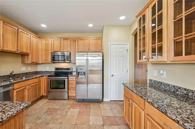 a kitchen with stainless steel appliances granite countertop a stove a sink and a refrigerator