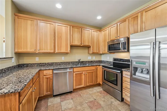a kitchen with stainless steel appliances granite countertop a stove top oven microwave and refrigerator