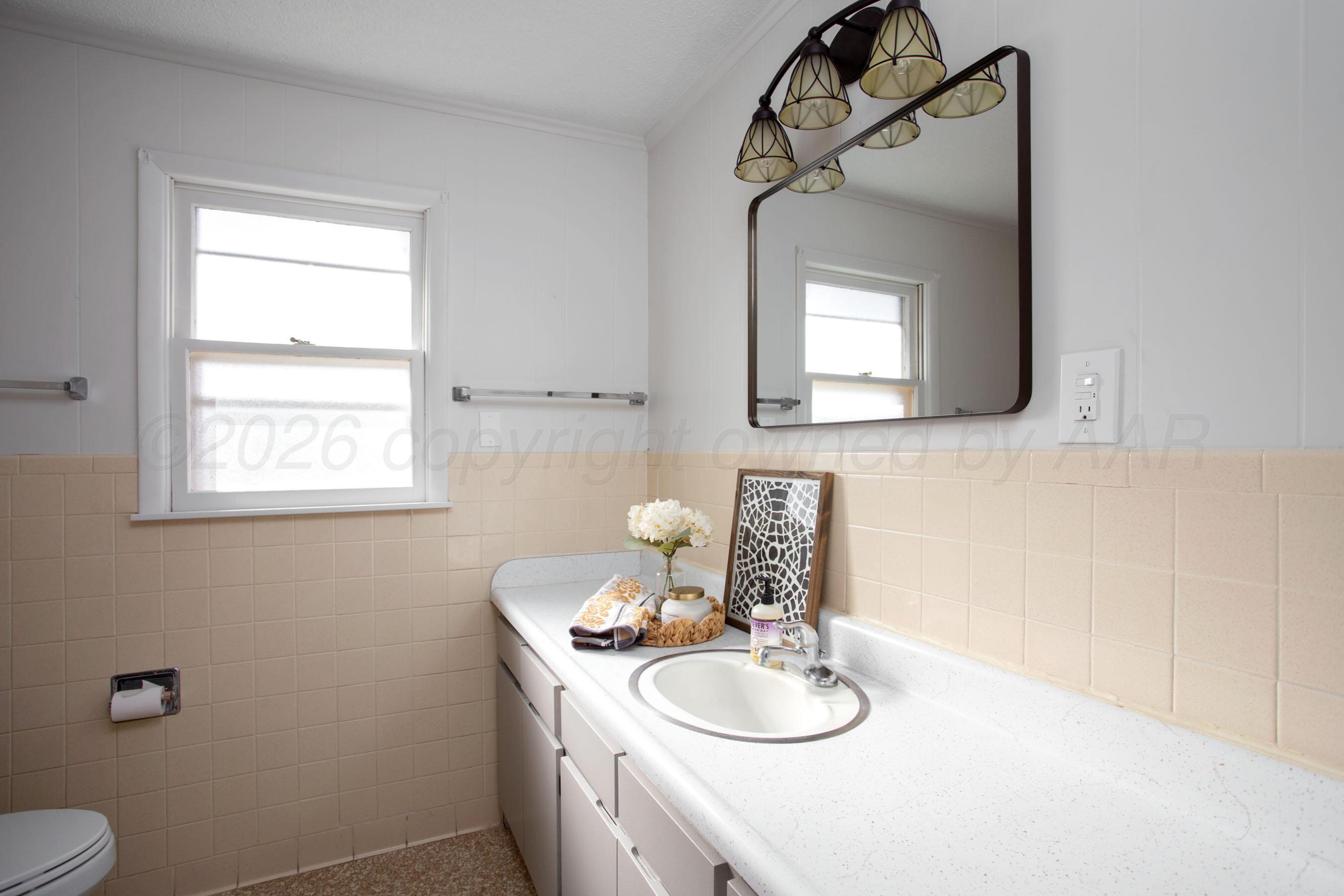 1107 Main Street Panhandle, TX 79068 - Photo 18 of 24 a bathroom with a toilet a sink and mirror