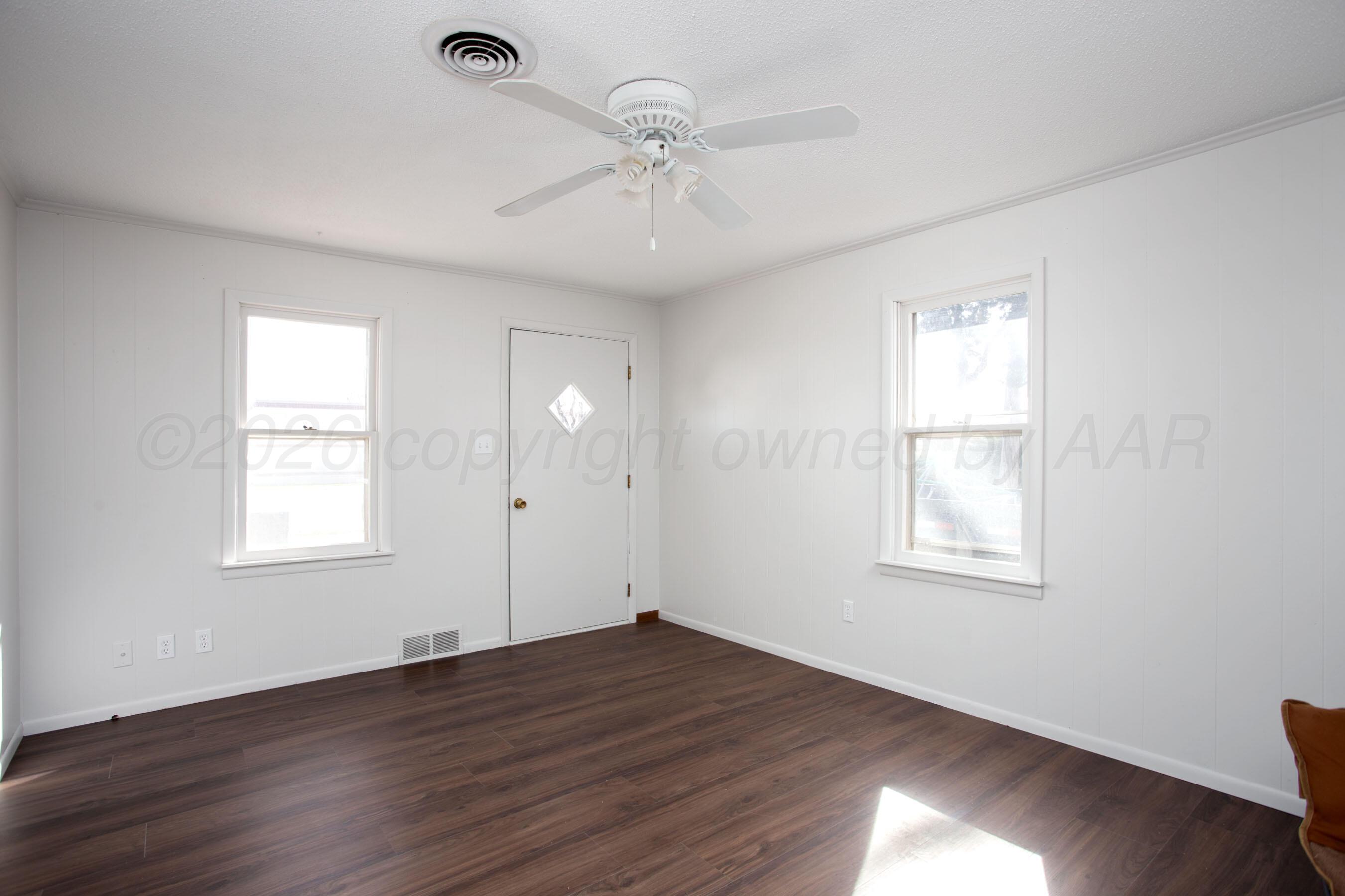 1107 Main Street Panhandle, TX 79068 - Photo 7 of 24 an empty room with wooden floor windows and fan