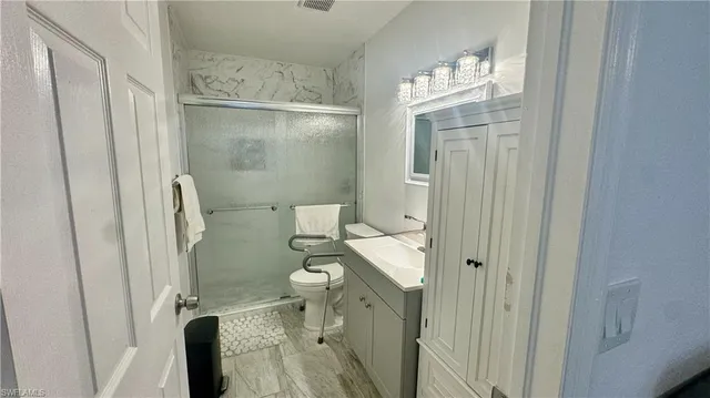 a bathroom with a granite countertop shower a toilet and a sink