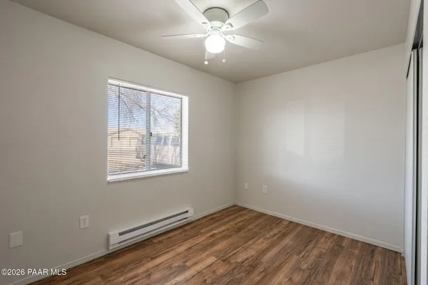 a view of an empty room with window and wooden floor