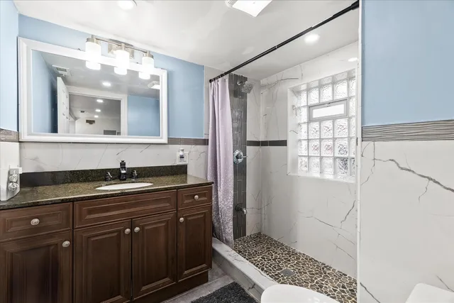 a bathroom with a granite countertop sink a mirror and a shower