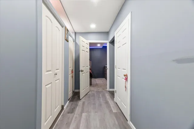 a view of a hallway with wooden floor and a bathroom