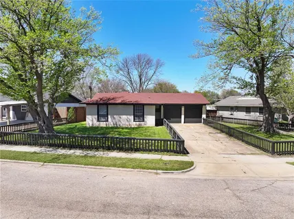 a front view of a house with a garden and trees