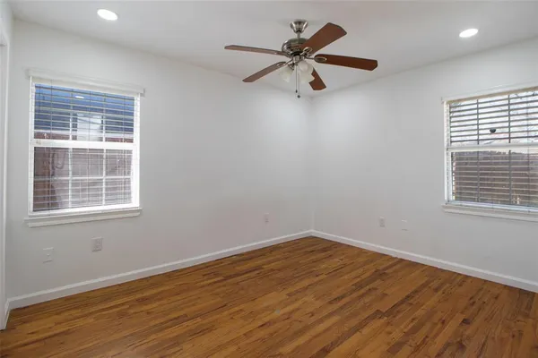 a view of a big room with wooden floor and windows