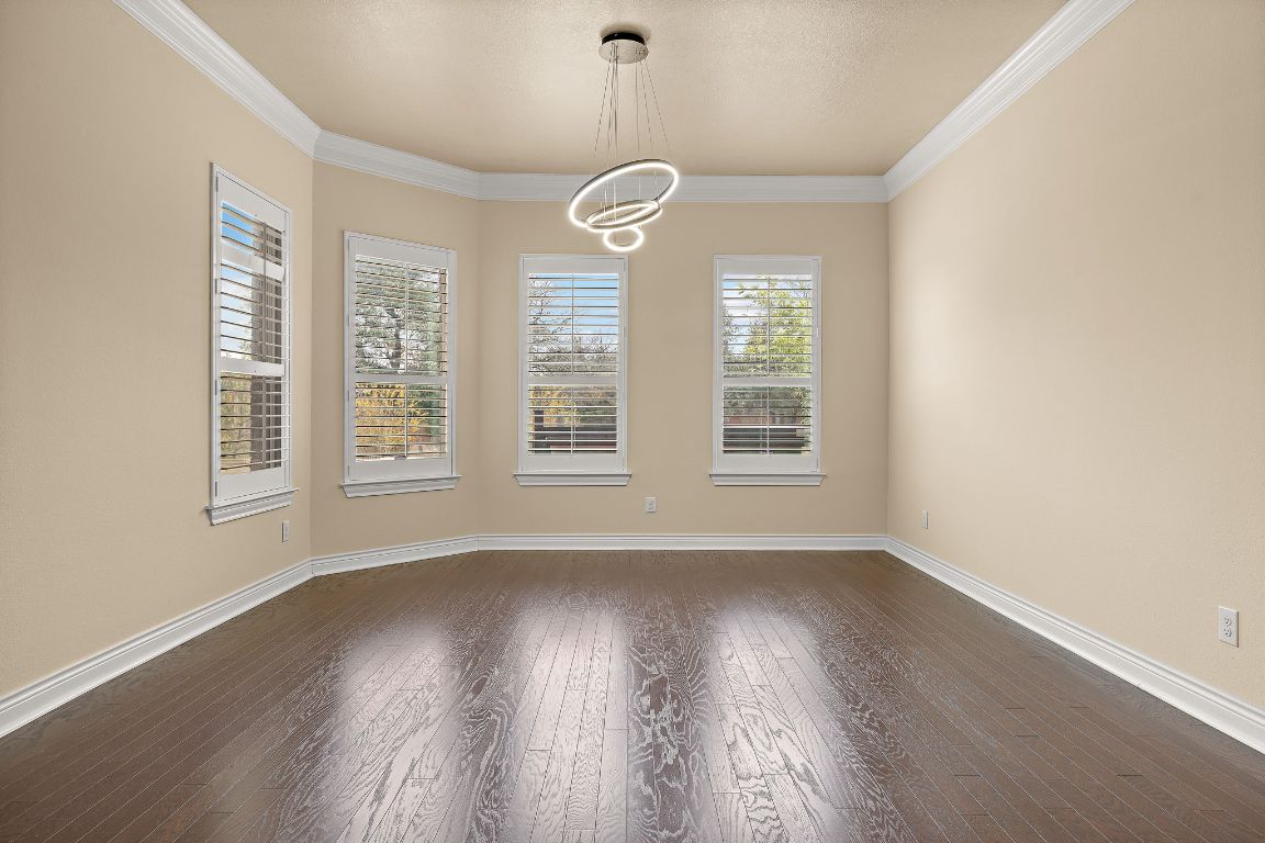 174 Estrella Crossing Georgetown, TX 78628 - Photo 15 of 39 Unfurnished dining area featuring ornamental molding, dark wood-type flooring, and a chandelier