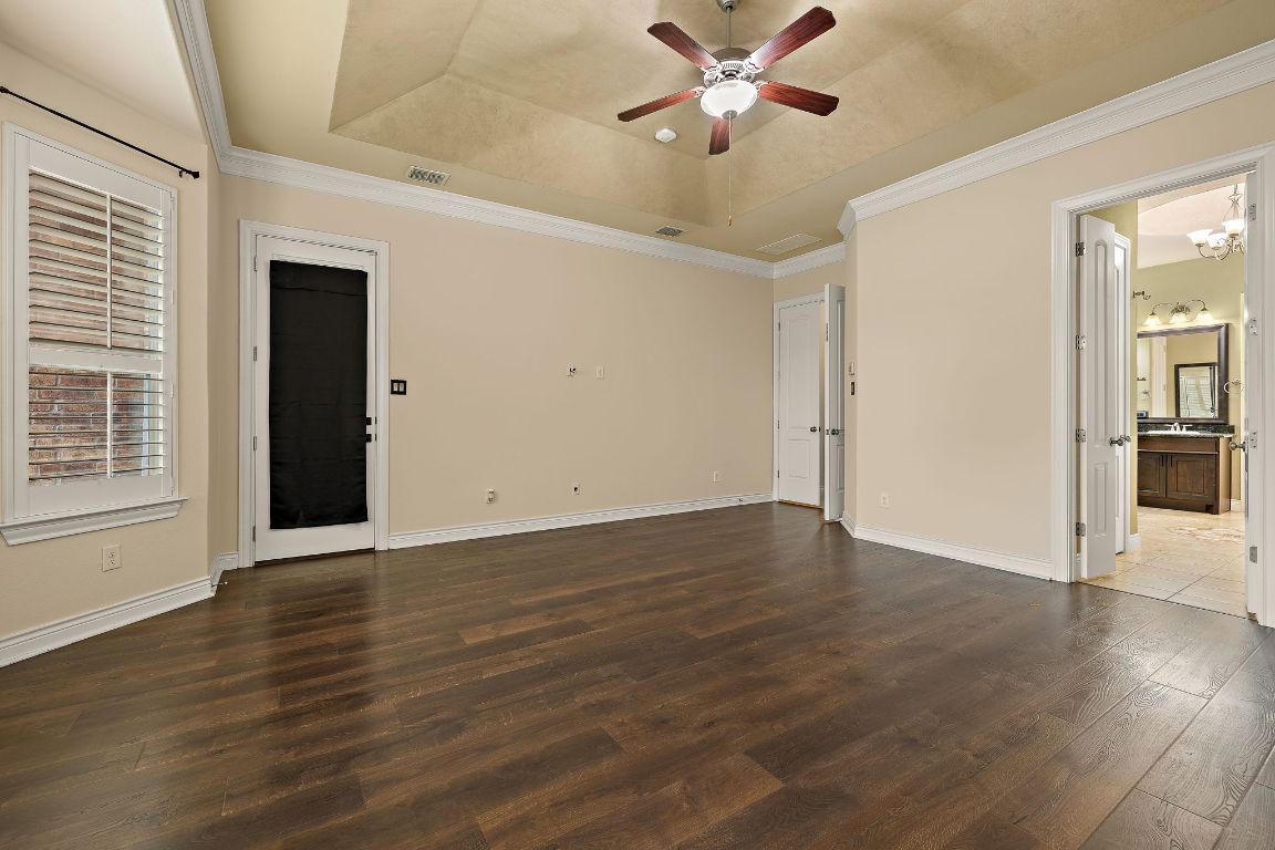 174 Estrella Crossing Georgetown, TX 78628 - Photo 17 of 39 Spare room featuring crown molding, a raised ceiling, dark wood-style flooring, and ceiling fan
