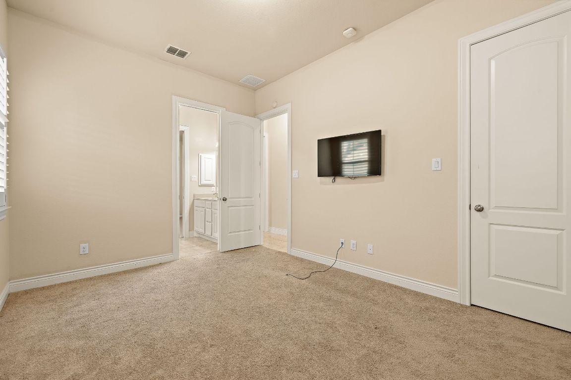 174 Estrella Crossing Georgetown, TX 78628 - Photo 27 of 39 Unfurnished bedroom with light colored carpet and connected bathroom
