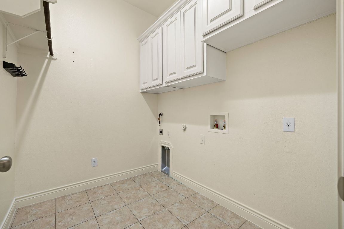 174 Estrella Crossing Georgetown, TX 78628 - Photo 31 of 39 Laundry room featuring gas dryer hookup, cabinet space, light tile patterned flooring, washer hookup, and hookup for an electric dryer