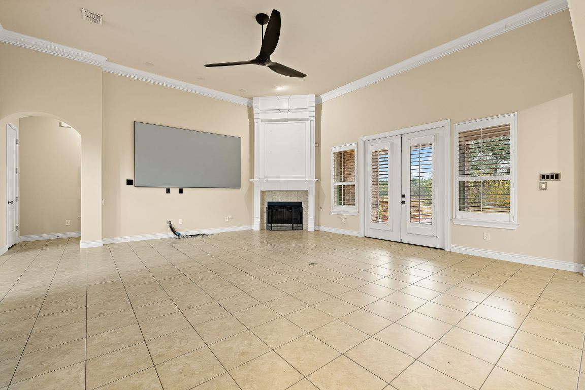 174 Estrella Crossing Georgetown, TX 78628 - Photo 8 of 39 Unfurnished living room with french doors, a ceiling fan, ornamental molding, arched walkways, and light tile patterned floors