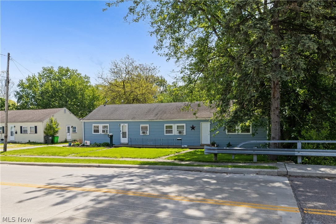 68-70 East Sunset Drive Rittman, OH 44270 - Photo 5 of 49 Blue siding exterior with a white front door, multiple white-trimmed windows, and a manicured front lawn