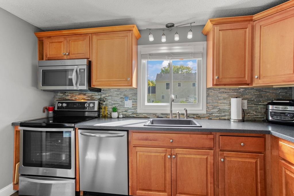 70 Underhill Street Nashua, NH 03060 - Photo 13 of 39 a kitchen with stainless steel appliances granite countertop a sink stove and microwave