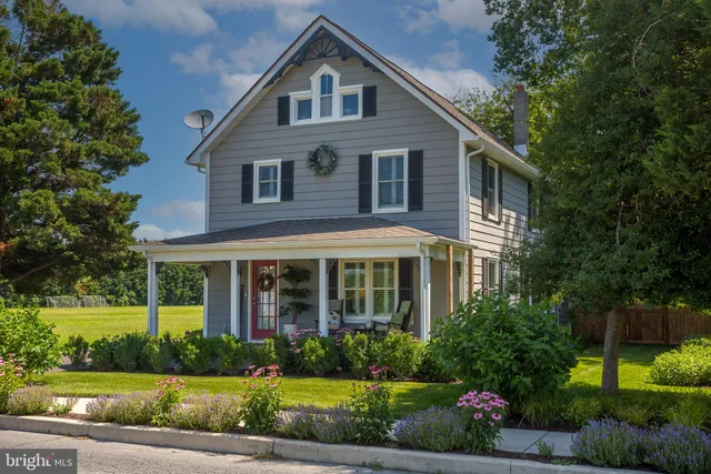 a view of a white house next to a yard with big trees