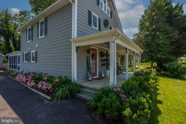 a view of a house with potted plants and a flower garden