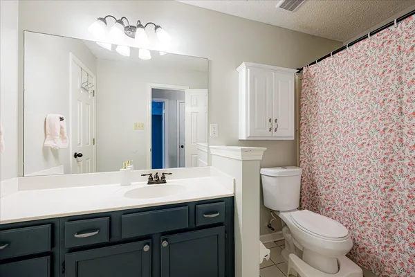 a bathroom with a granite countertop toilet sink and mirror