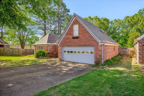 a view of a house with a yard and a large tree