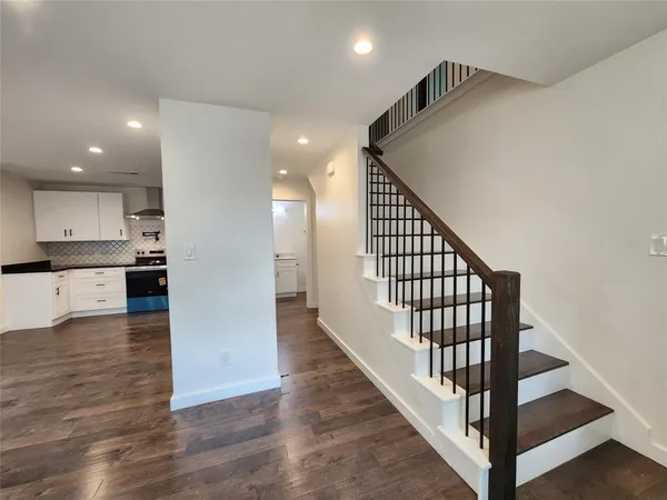 a view of a hallway with wooden floor and staircase