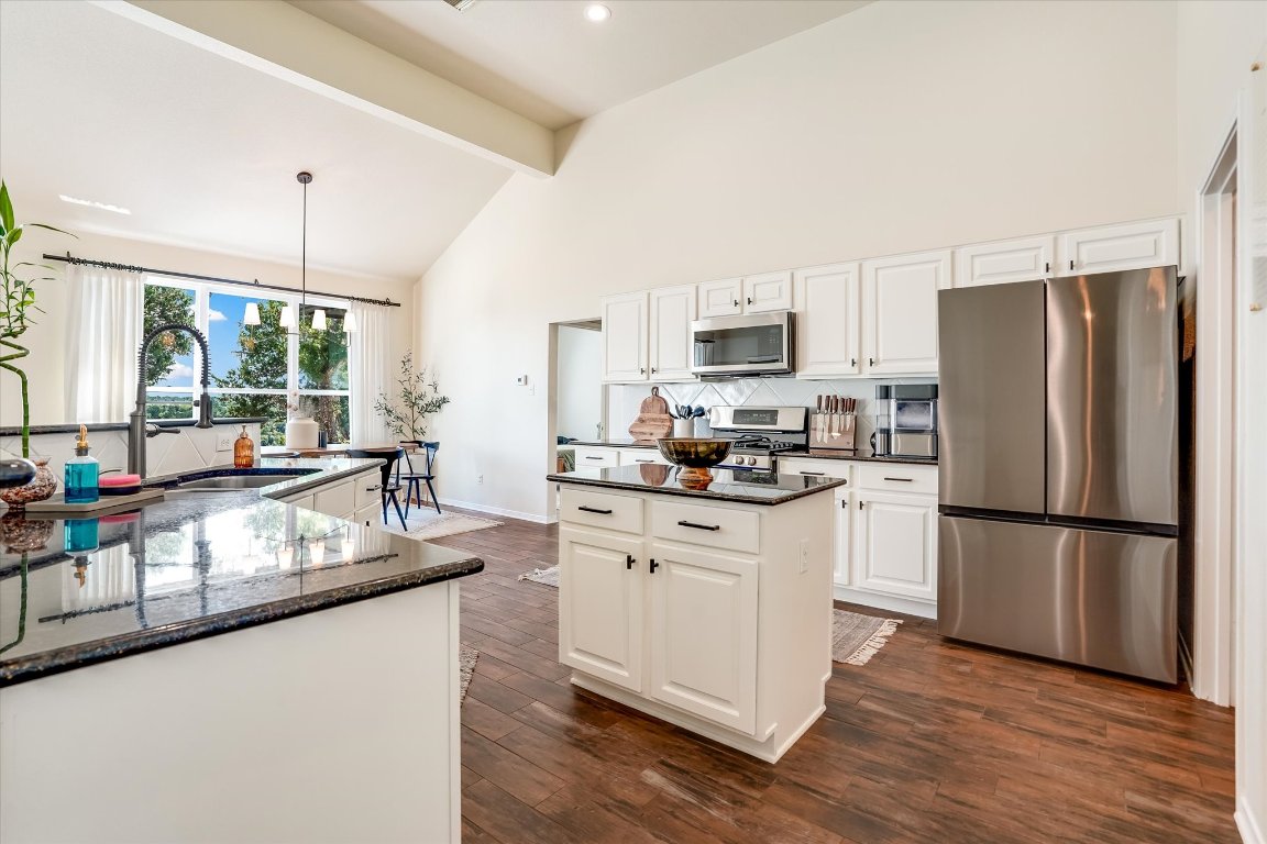 13201 North Ridge Circle Leander, TX 78641 - Photo 12 of 33 a kitchen with kitchen island granite countertop a stove a sink a refrigerator and a dining table with wooden floor