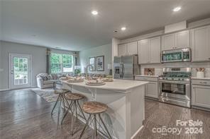 8065 Scarlet Maple Lane, Unit 2044 Tega Cay, SC 29708 - Photo 2 of 4 a kitchen with kitchen island a stove a table and chairs in it