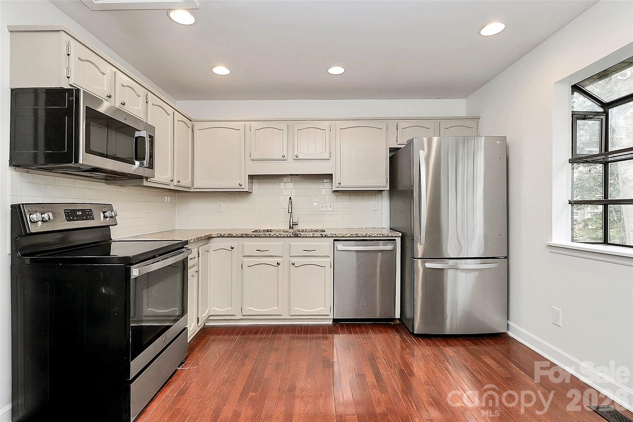 9421 Fairway Ridge Road Charlotte, NC 28277 - Photo 11 of 36 a kitchen with stainless steel appliances granite countertop a refrigerator stove a sink and white cabinets with wooden floor
