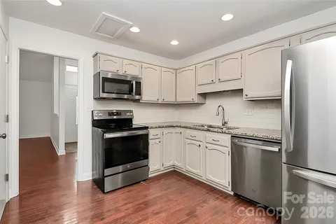 a kitchen with stainless steel appliances granite countertop a stove top oven a sink and a refrigerator