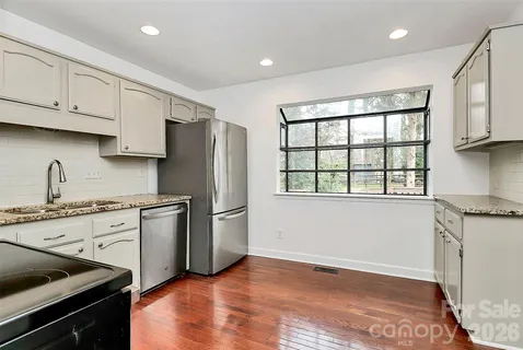 a kitchen with granite countertop a refrigerator stove top oven and sink