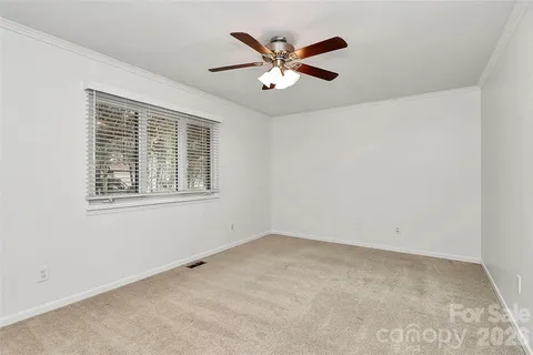 an empty room with ceiling fan and windows