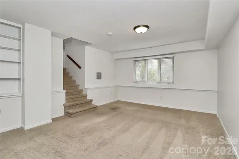 a view of an empty room with stairs and a bathroom