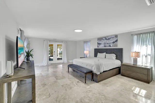 a spacious bedroom with a bed and a flat tv screen on dresser